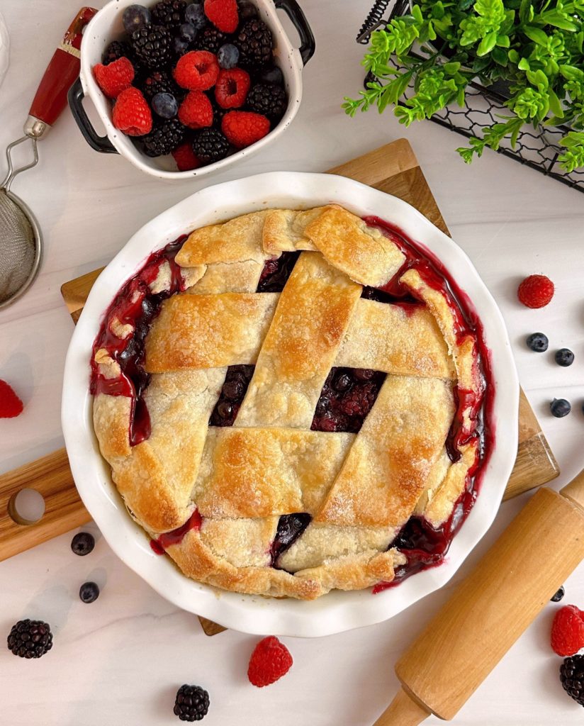 Triple Berry Deep Dish Galette in a white pie dish and a dish of fresh berries.