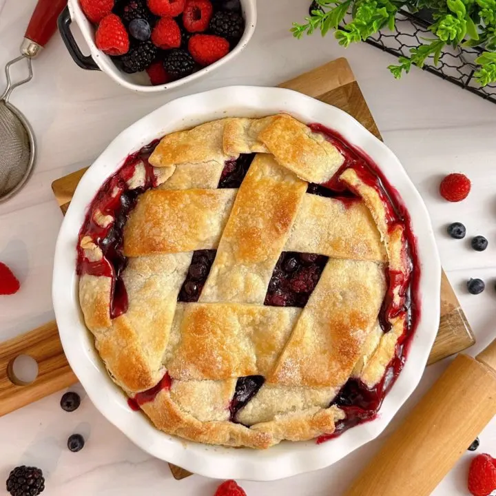 Triple Berry Deep Dish Galette in a white pie dish and a dish of fresh berries.