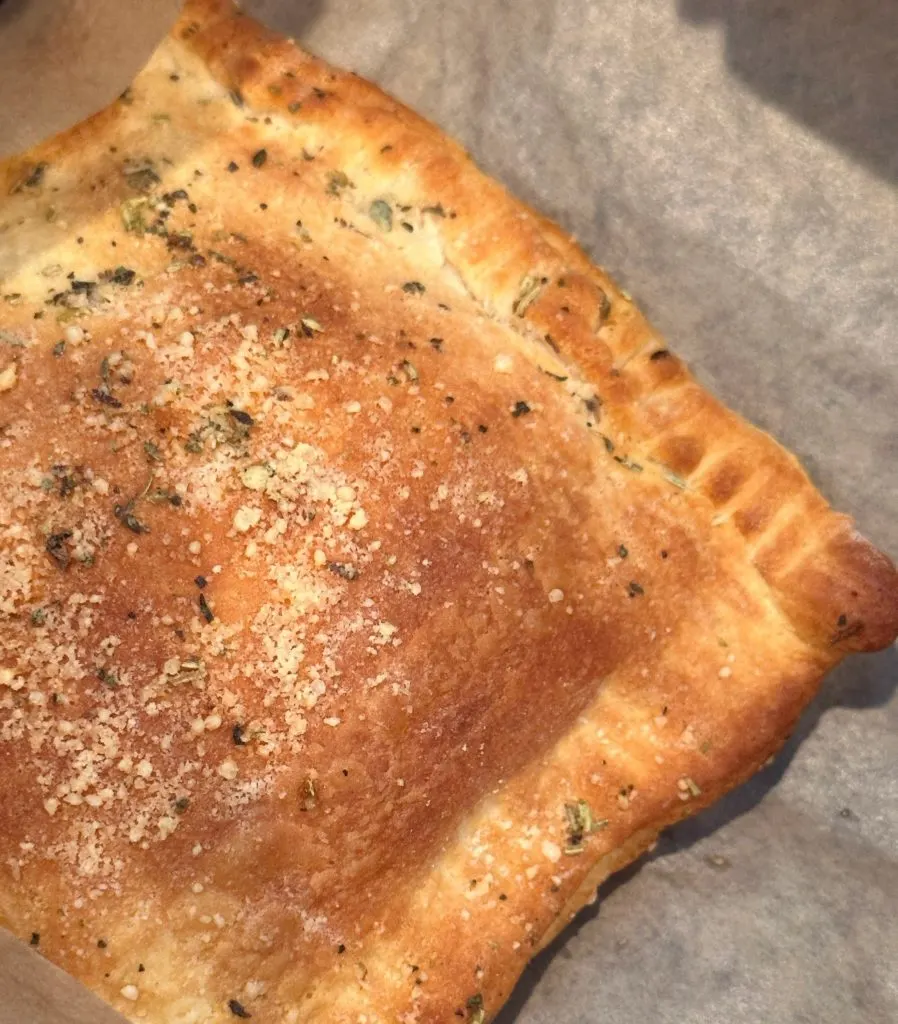 Baked Calzone in the air fryer basket with parchment paper.
