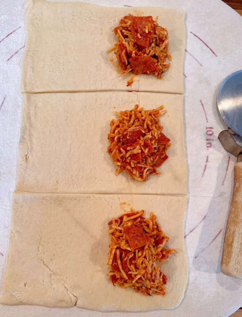 Placing filling on one half of each prepared portion of pizza dough.