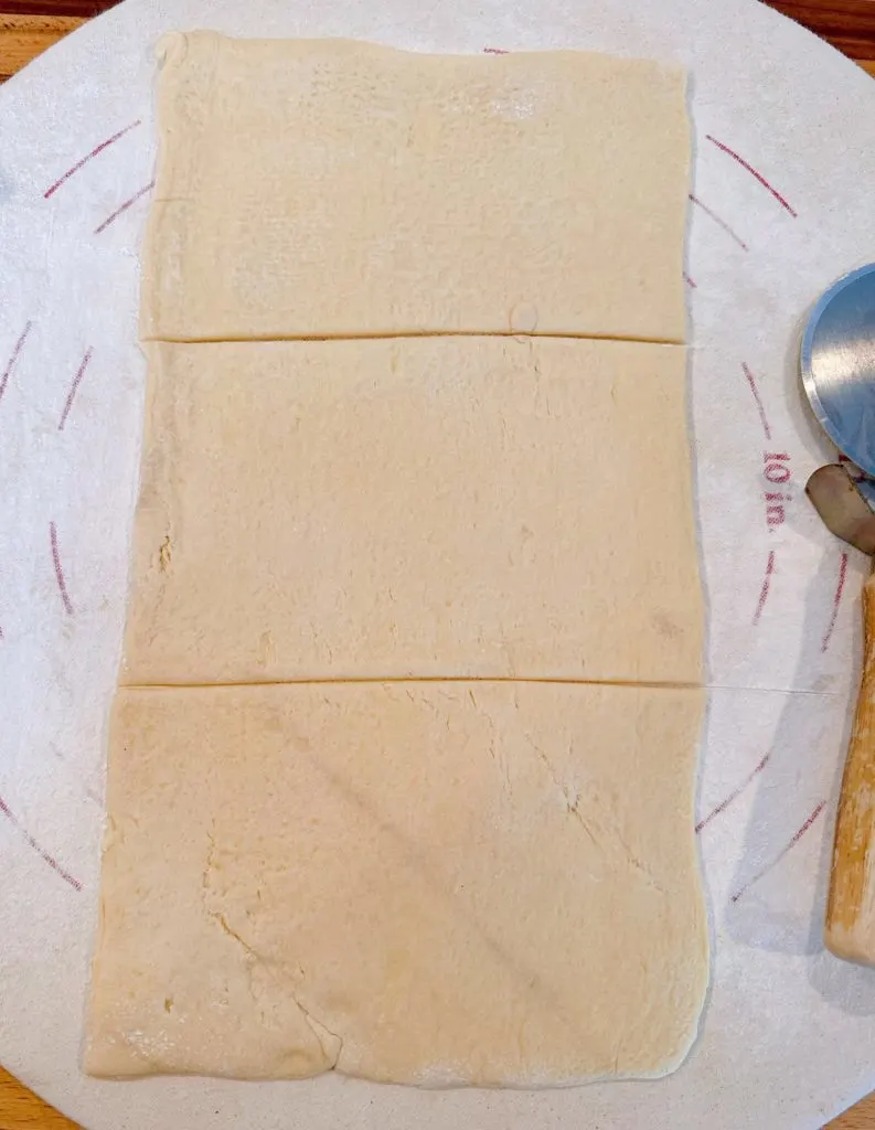 Crescent Roll dough on a lightly floured surface. Cut into three sections for calzones.