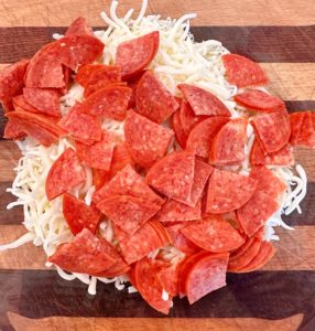 Medium bowl filled with cheese, pepperoni.