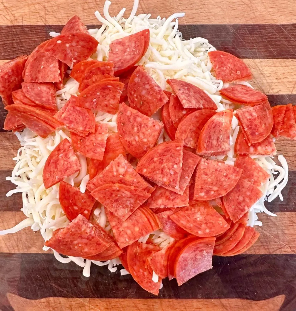 Medium bowl filled with cheese, pepperoni.
