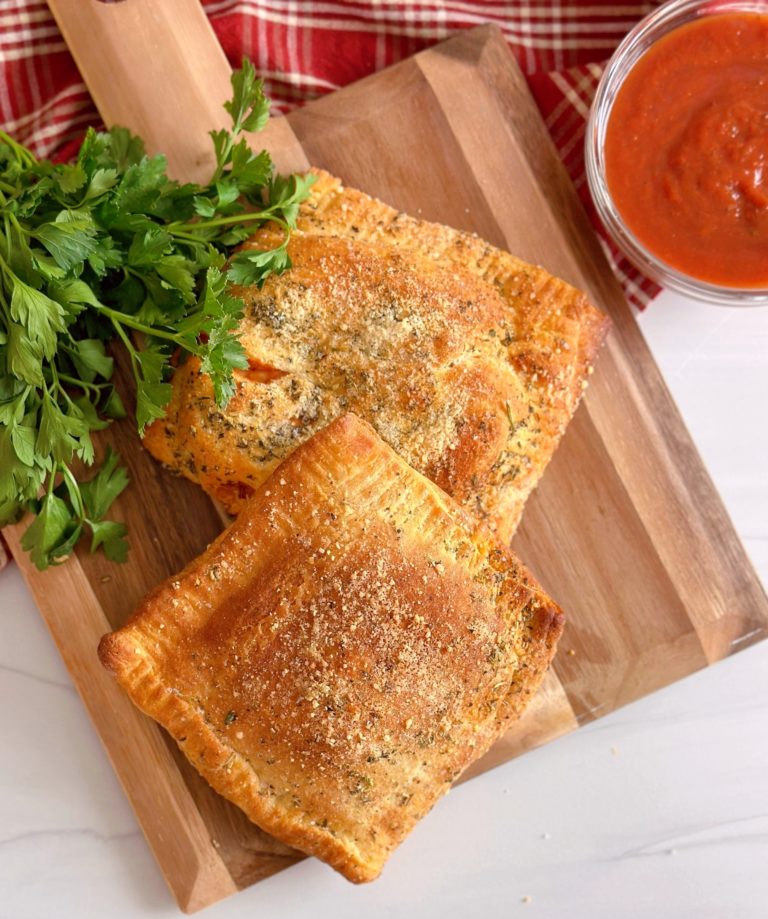 Overhead photo of Air Fryer Calzones, two of them, on a wooden board.