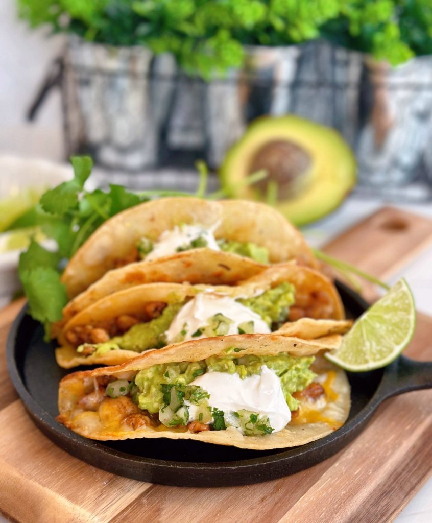 Easy Chicken Tacos with guacamole and sour cream on a skillet.