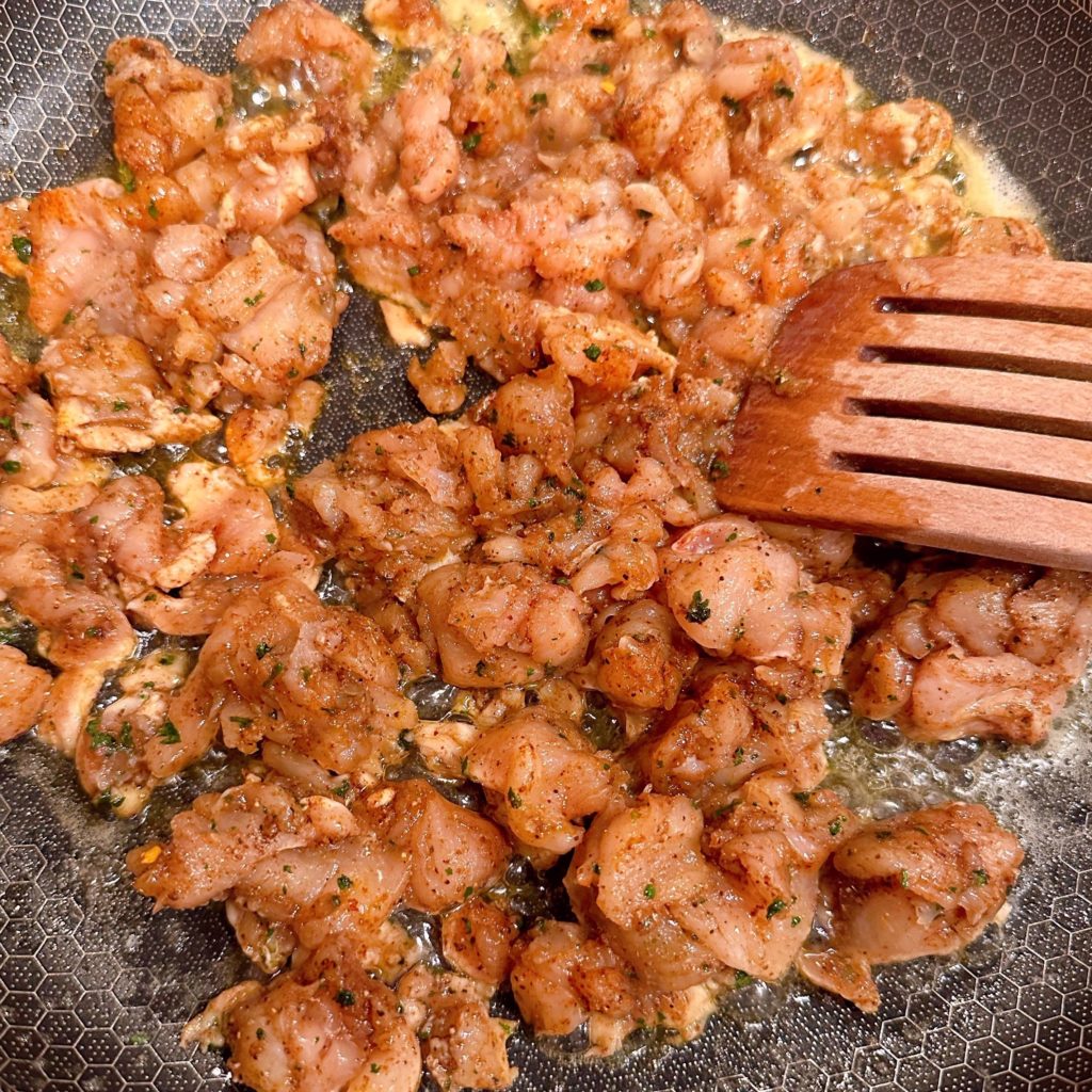 Raw chicken in a hot skillet being cooked.