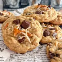 Ultimate Loaded Trash Can Chocolate Chip Cookies piled high on newspaper parchment print.