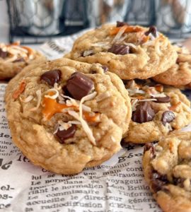 Ultimate Loaded Trash Can Chocolate Chip Cookies piled high on newspaper parchment print.