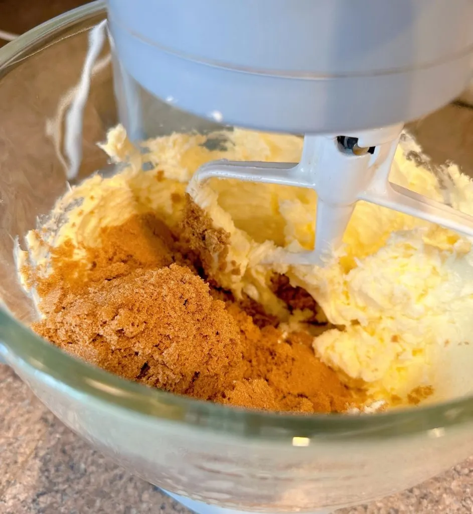 Adding brown sugar, eggs, and vanilla to creamed butter in mixing bowl.