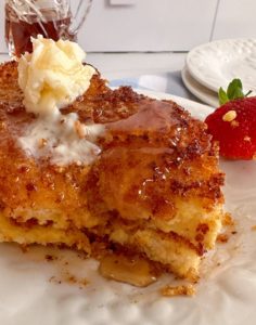 French Toast with syrup and butter and a few bites missing.