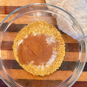 Cornflake crumbs with cinnamon and sugar in a medium glass bowl.