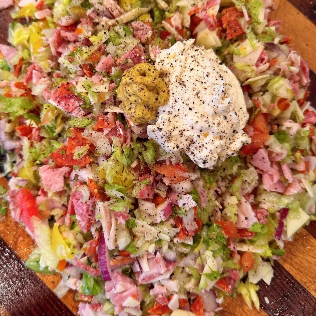 Mayo and mustard dressing ingredients on top of chopped ingredients.