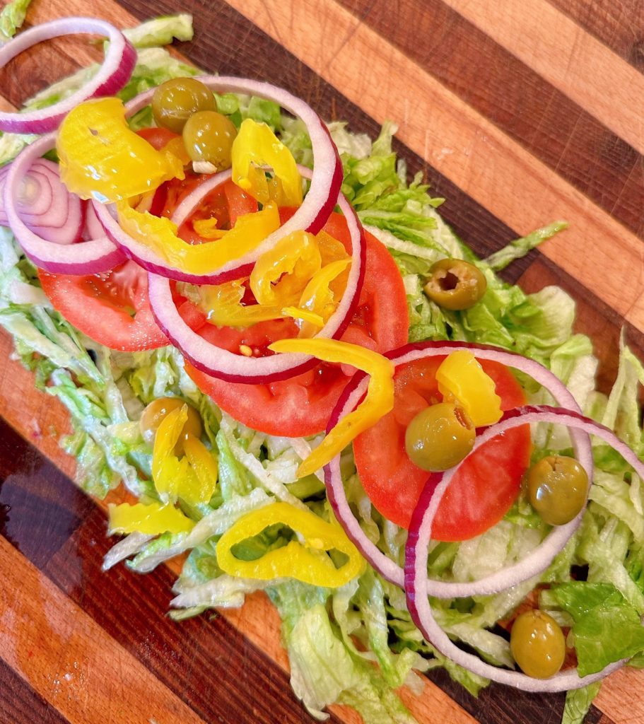 Layer of Italian Grinder ingredients on cutting board.