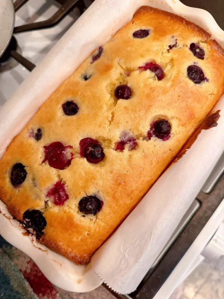 Loaf of Lemon Bread in pan on a cooling rack.