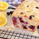 Lemon Blueberry Bread sliced with glaze on parchment paper.