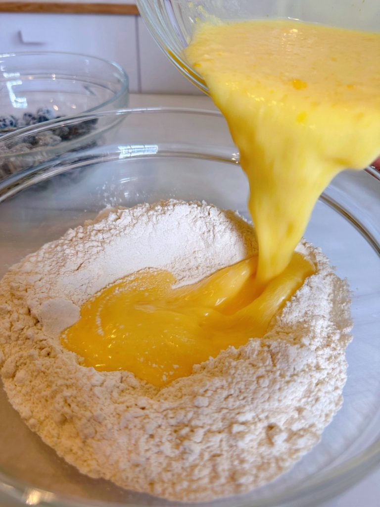 Pouring wet ingredients into the well in the center of the dry ingredients.