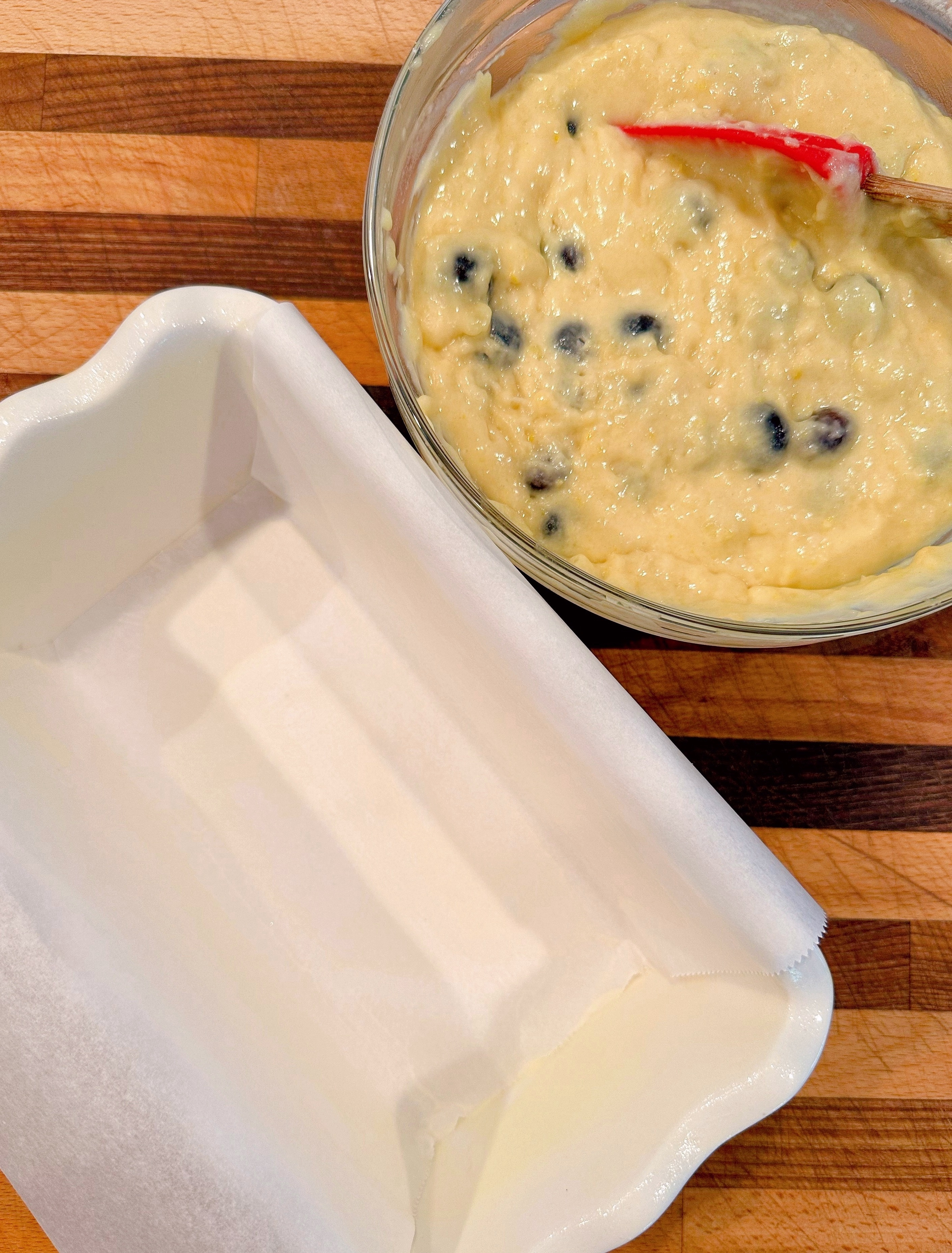 Prepared blueberry bread batter with prepared loaf baking dish.