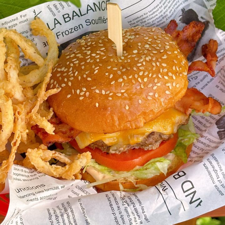 Ultimate Smash Burger on a printed piece of parchment paper with onion straws.