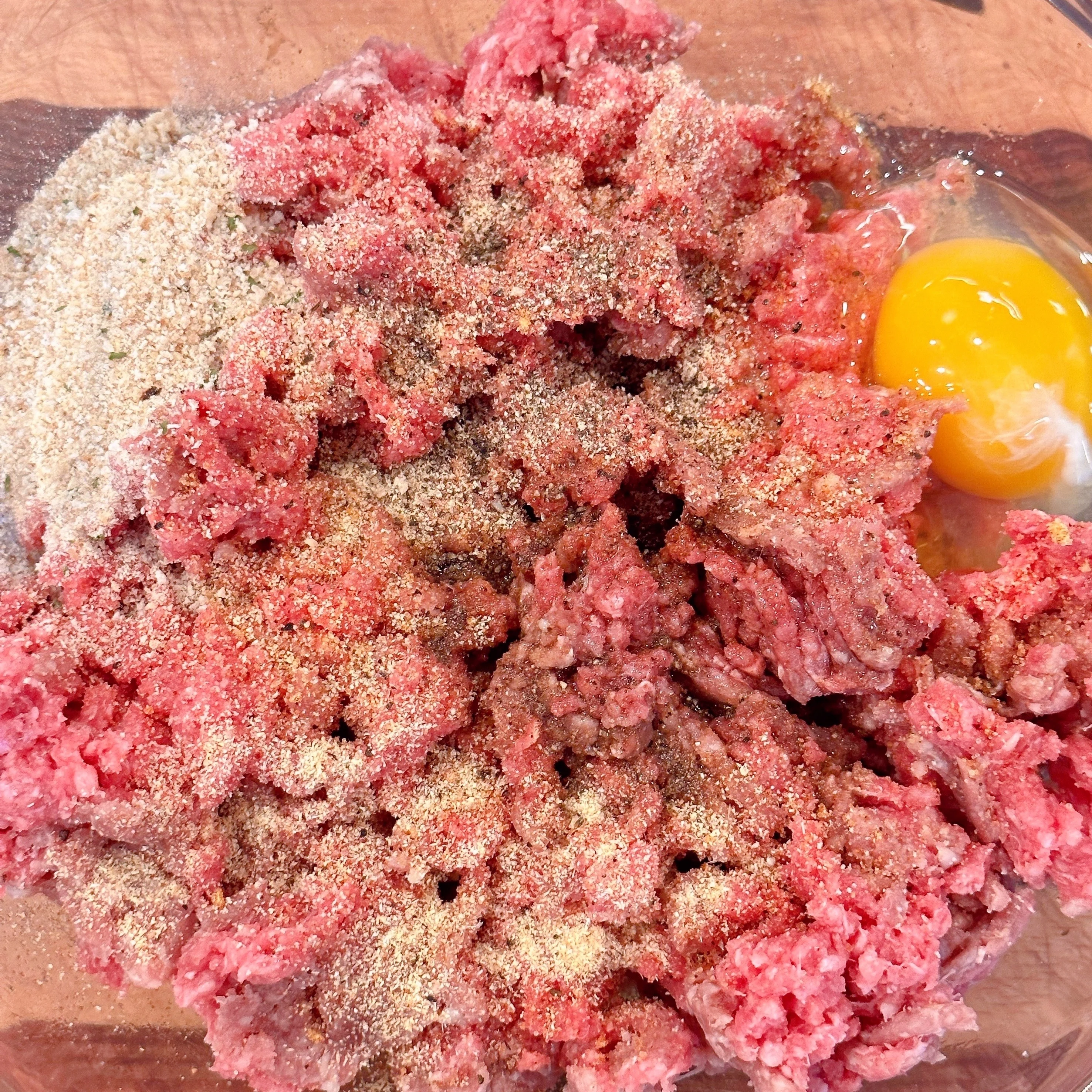 Large bowl with ground chuck, seasonings, egg, and bread crumbs.