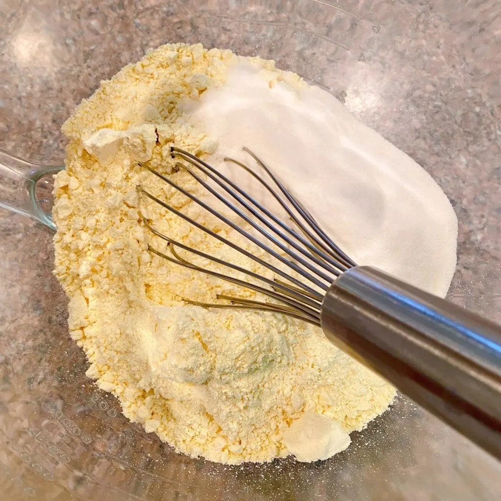 Cake mix in a bowl with jello mix and wire whisk.