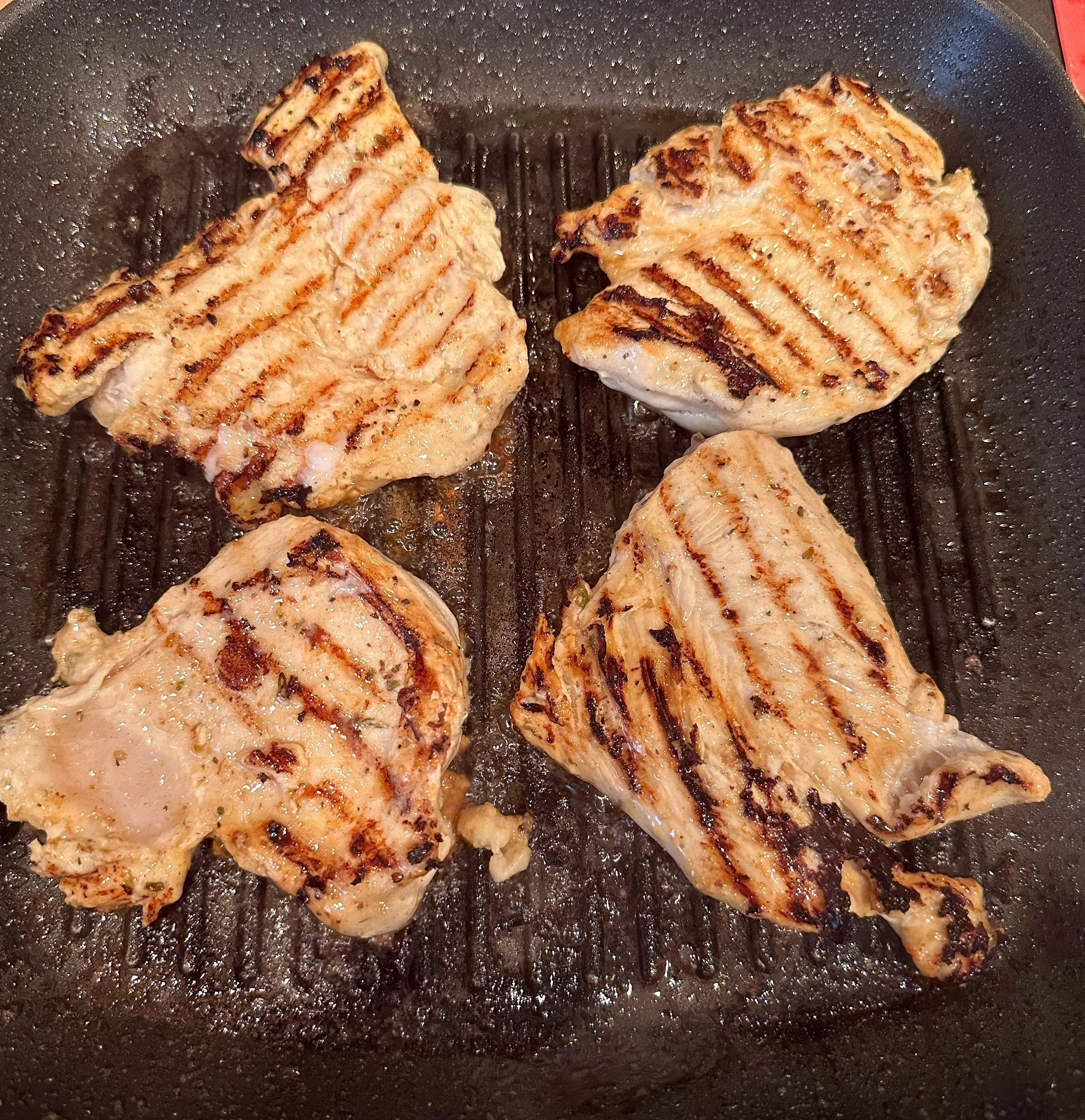 Chicken grilled on one side and cooking on the other.