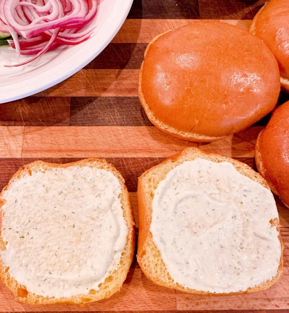 Dill sauce spread on the top and bottom of the buns.