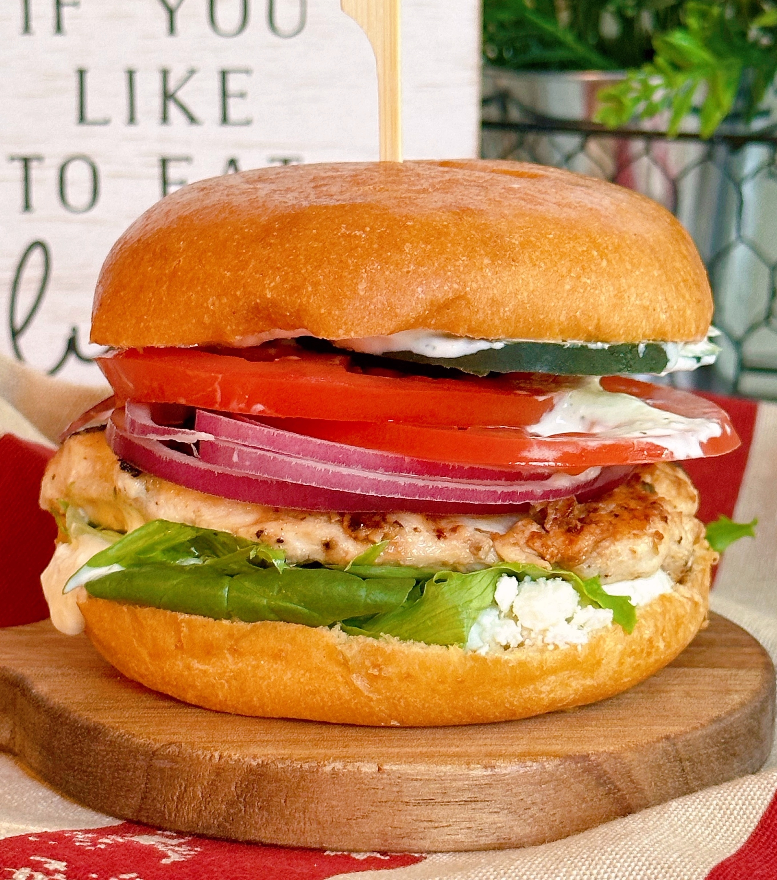 Mediterranean Chicken Sandwich with Dill Sauce up close on a wooden cutting board.