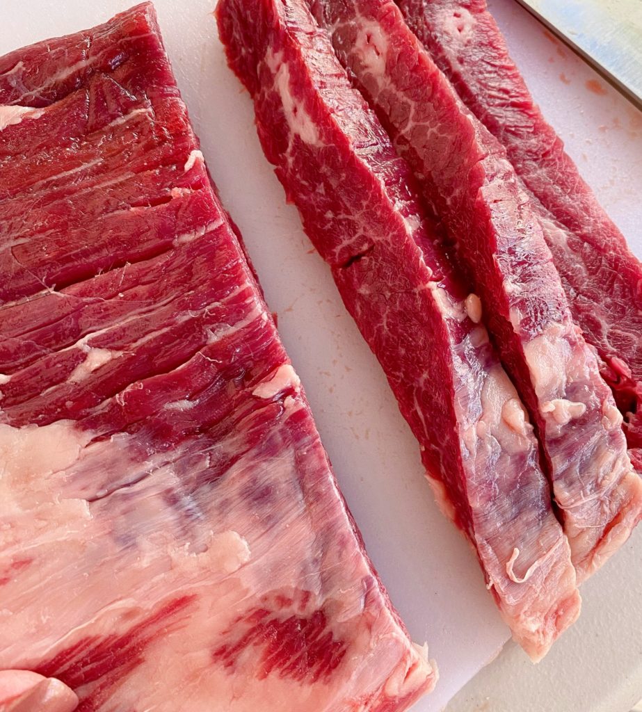 Flank Steak cut into thin strips for Fajitas on a cutting board.