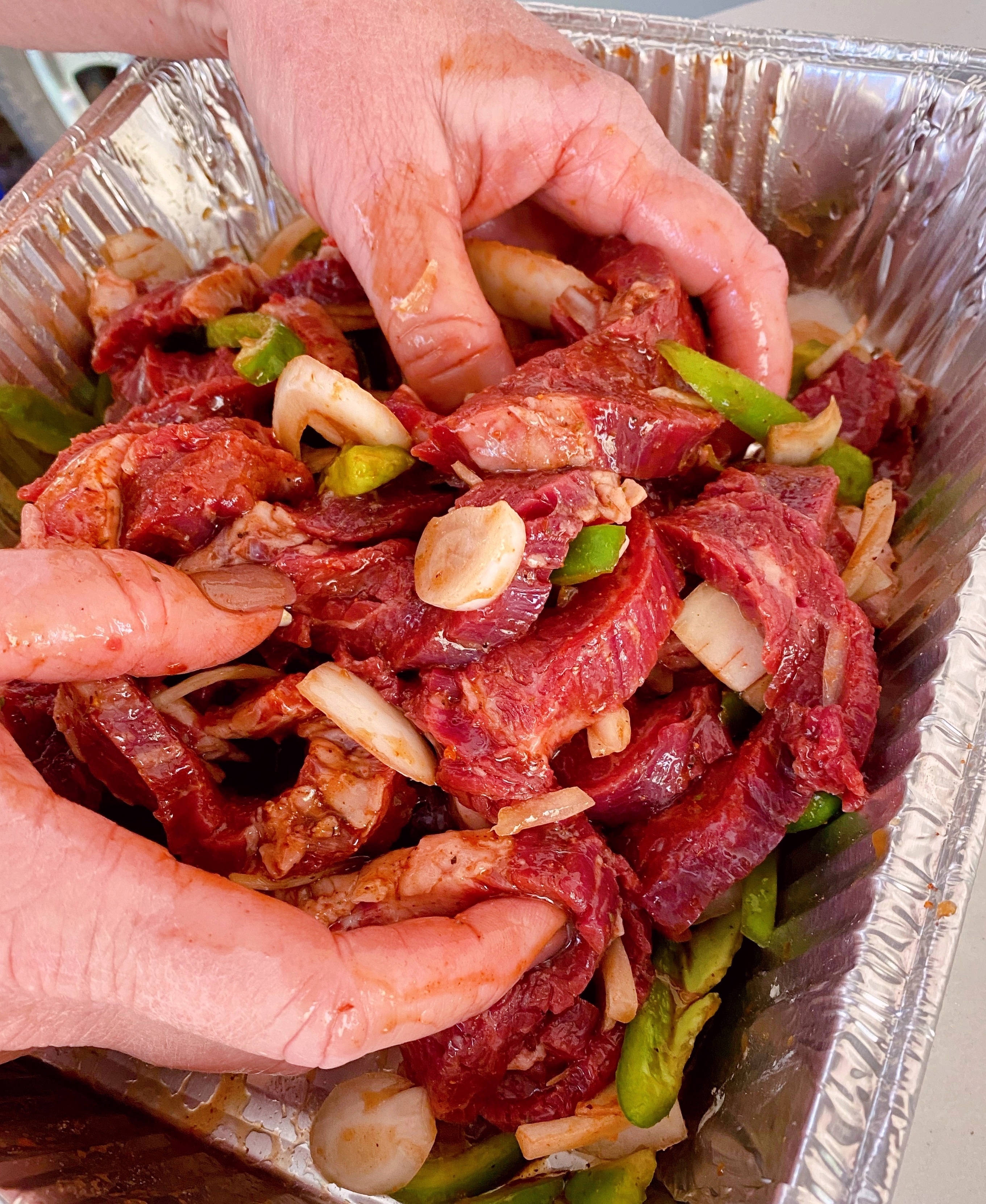 Tossing beat, peppers, and onions in marinade mixture.
