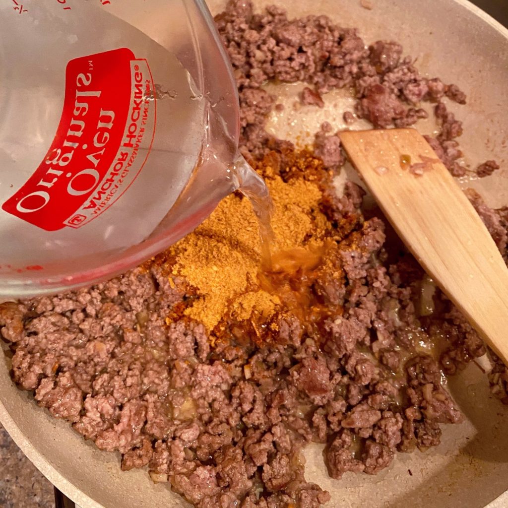 Browning ground beef, adding taco seasoning, and liquids.