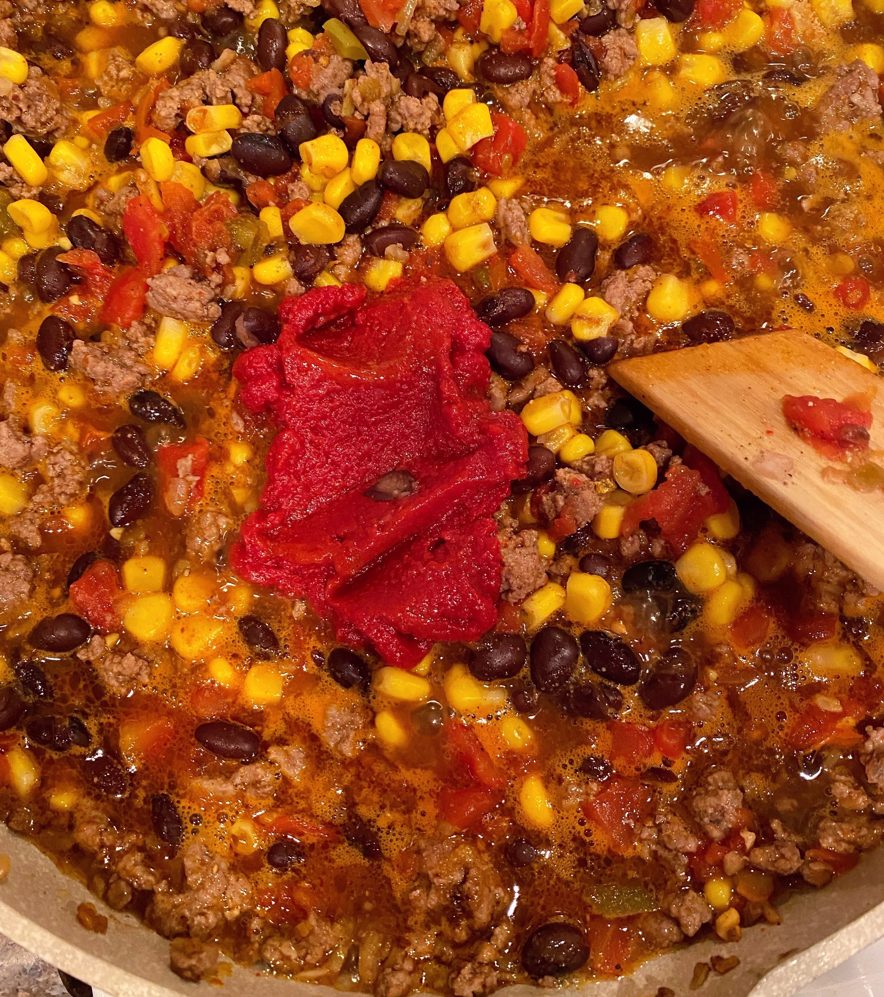 Addinto tomato paste to chili mixture in the skillet over medium-low heat.