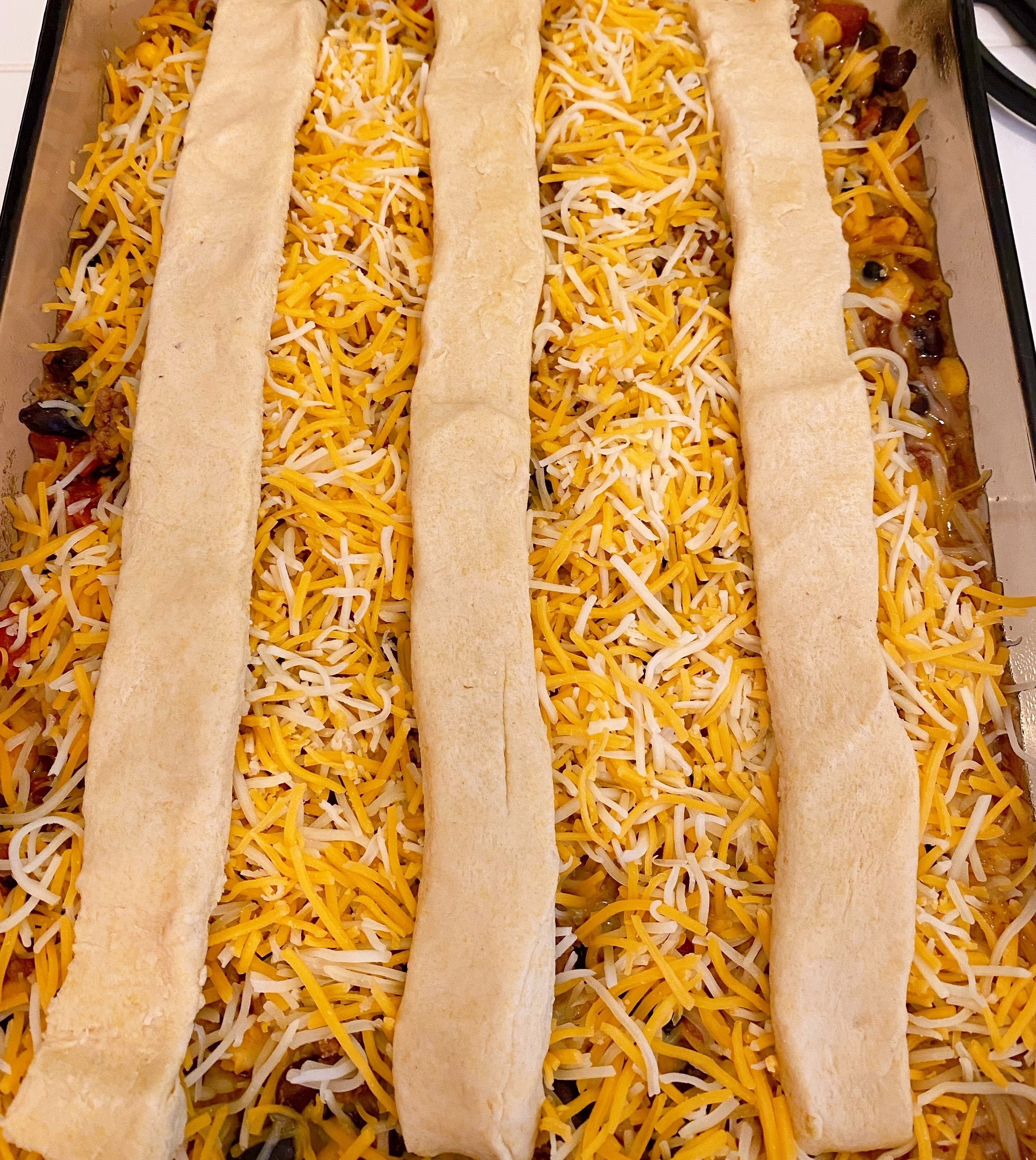 Cornbread sticks laid vertically across prepared casserole. 