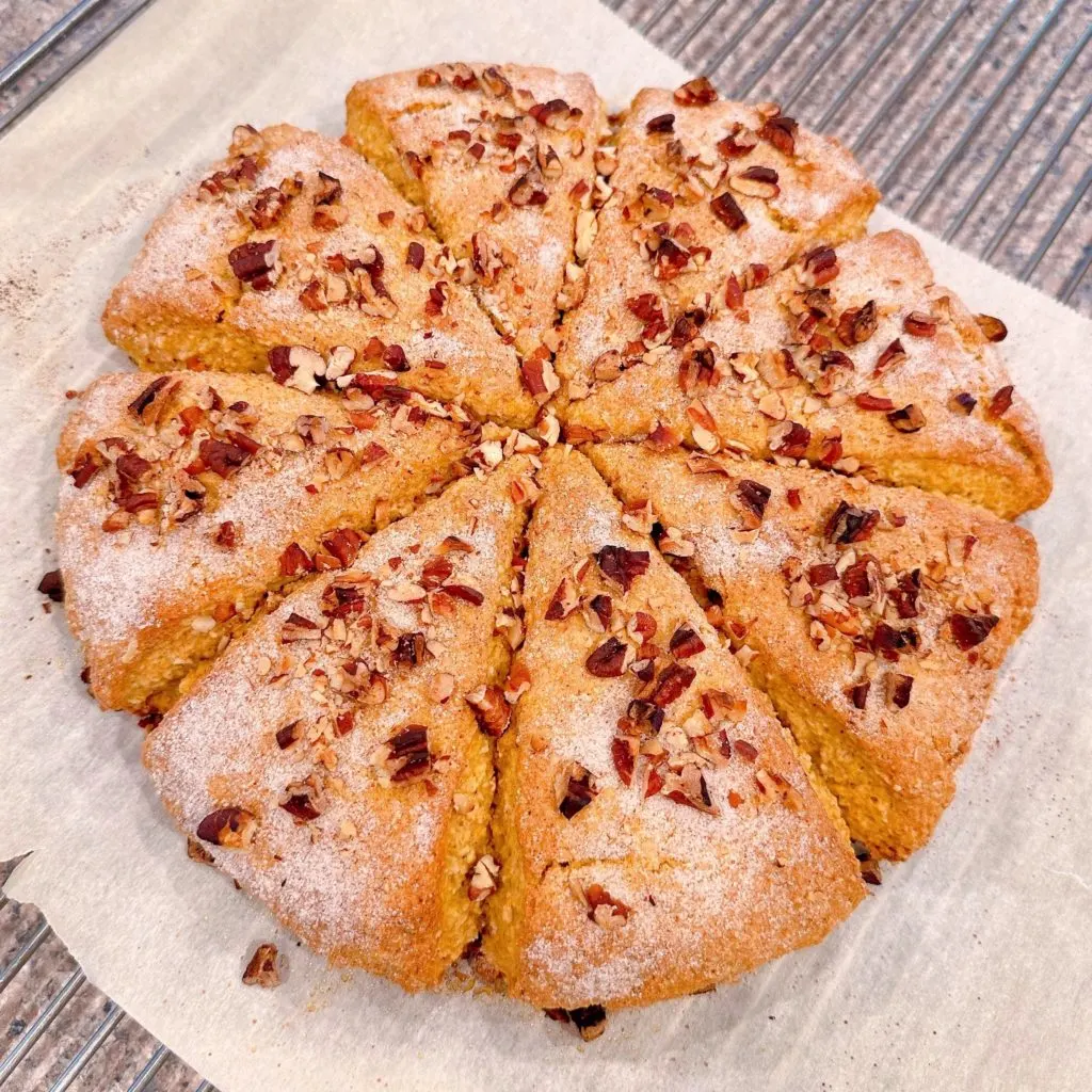 Baked scones on parchment paper on top of wire rack.