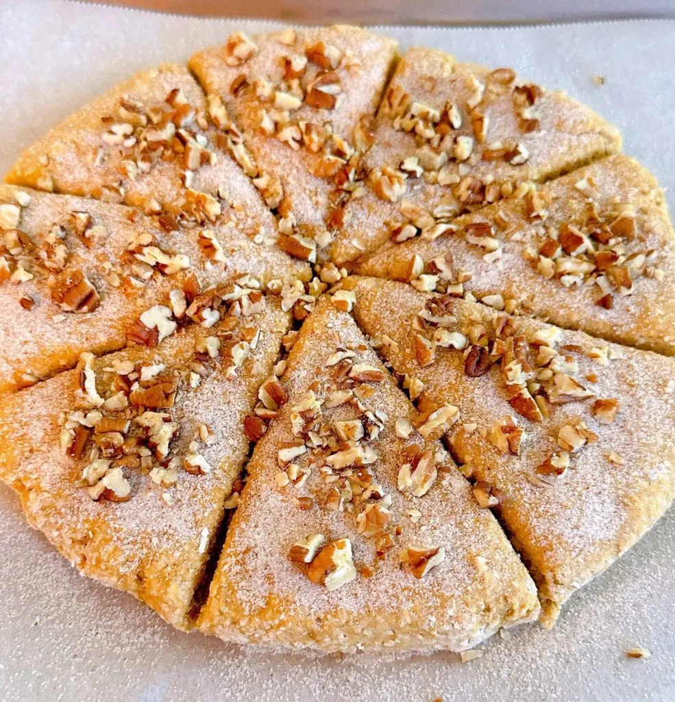 Scone dough topped with cinnamon sugar and chopped pecans.