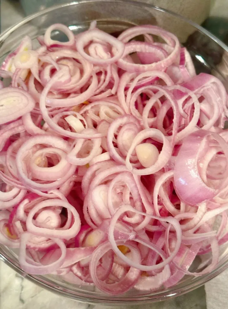 Shallots in a large bowl, separated into rings.