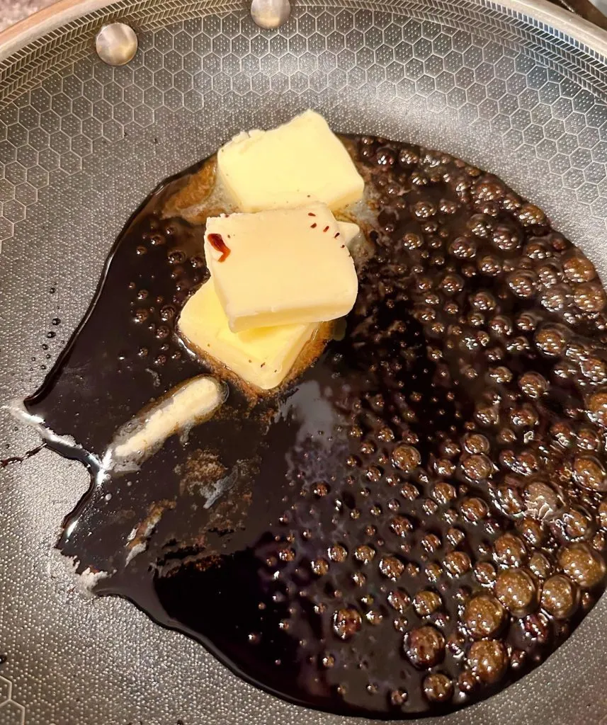 Adding butter to reduced balsamic and sugar in a large skillet.