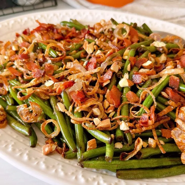 Balsamic Green Beans with Bacon, almonds, and fried shallots on a white platter.
