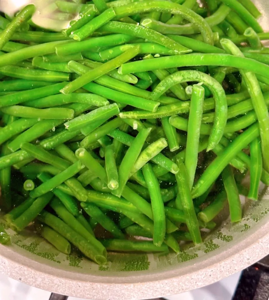 Green beans in a large pot of boiling water.
