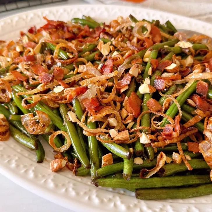 Balsamic Green Beans with shallots and almonds on white serving tray.