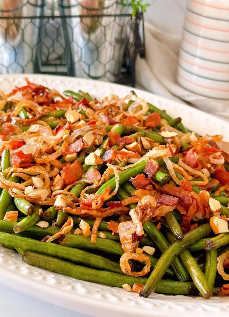 Balsamic Green Beans with bacon, almonds, and fried shallots on a white serving platter.