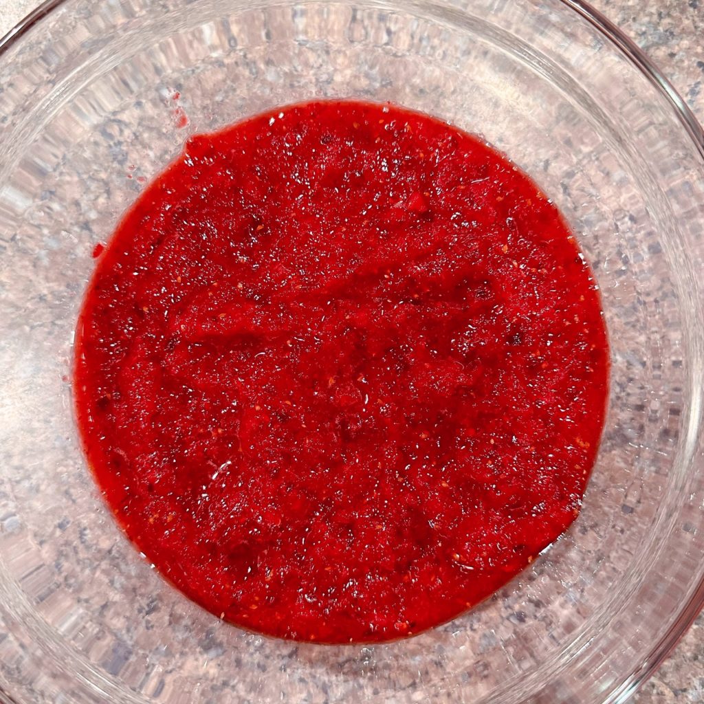 Ground cranberries with sugar in covered bowl ready to chill.