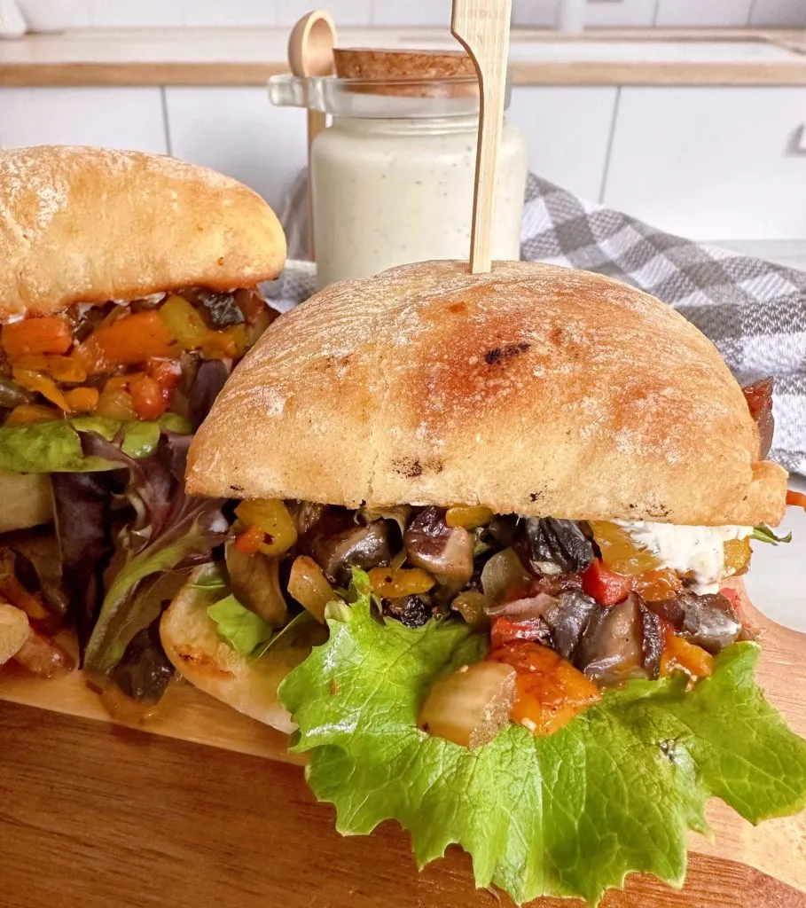 Greek Portobello Sandwiches with Dill Sauce in the background on a cutting board.