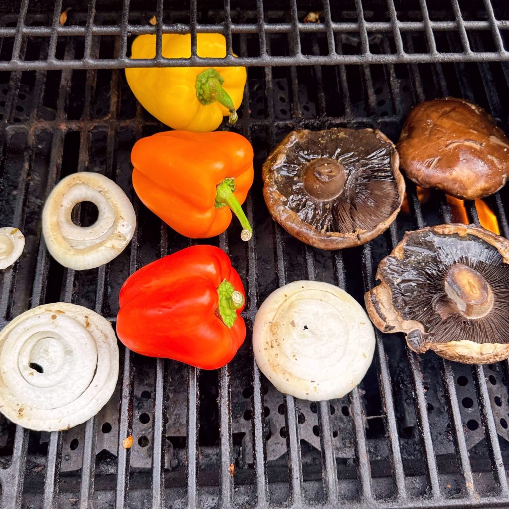 Grilling Mushrooms, peppers, and onions over heat of BBQ.