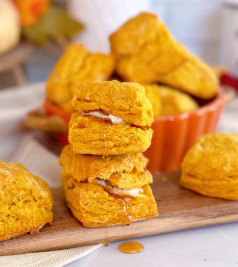 Pumpkin Buttermilk Biscuits stacked and dripping with honey and butter.