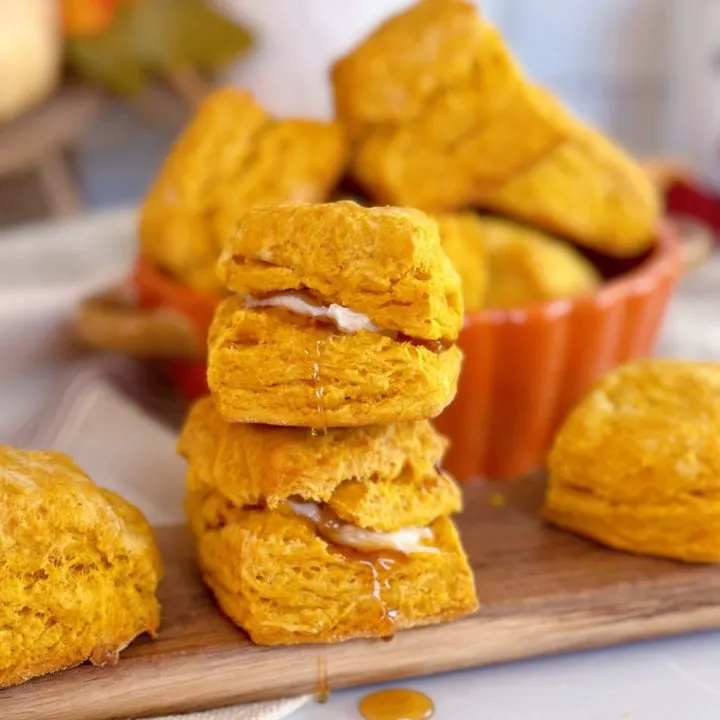 Pumpkin Buttermilk Biscuits stacked with honey and butter.