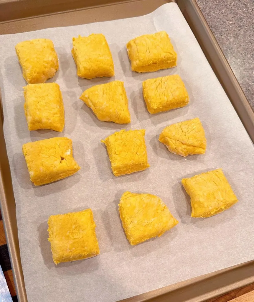 Arranging pumpkin biscuits on prepared baking sheet.