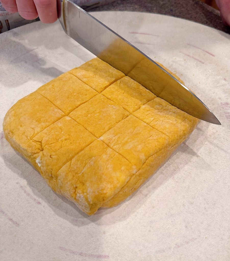 Pumpkin Biscuit Dough marked for 12 square biscuits on a floured surface.