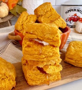 Pumpkin Biscuits stacked on a cutting board, stacked, with honey and butter.