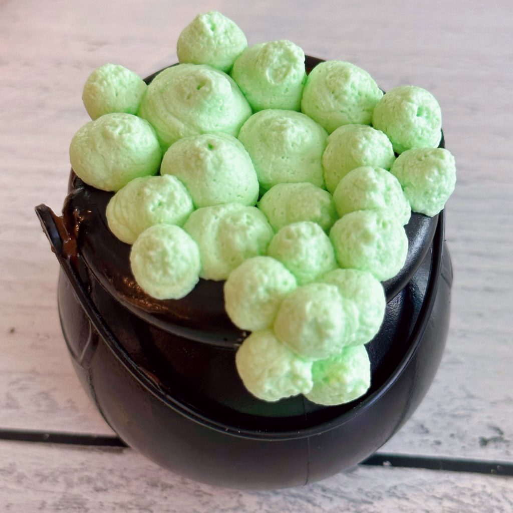 Cauldron covered in green bubble frosting dots.