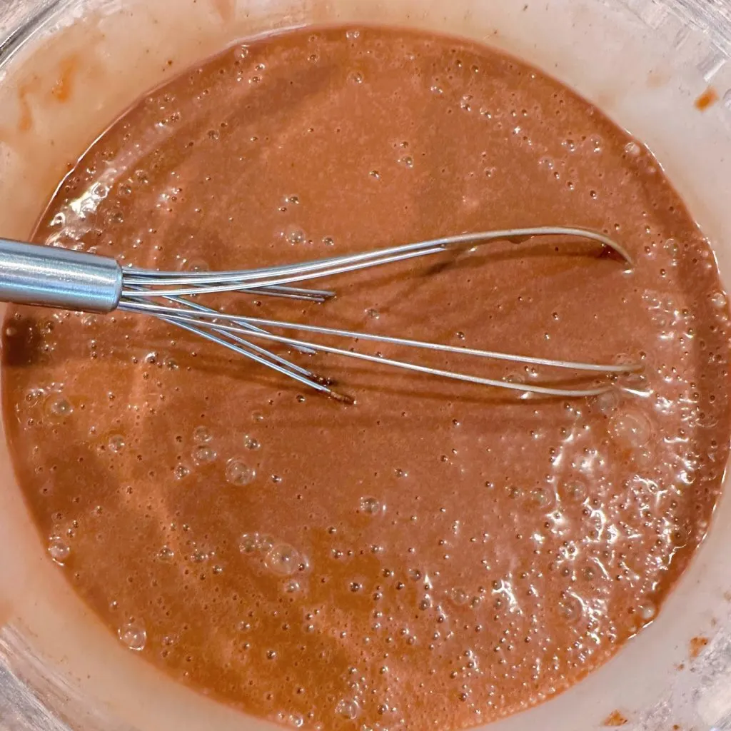 Whisking pudding mix and milk together in a large bowl.